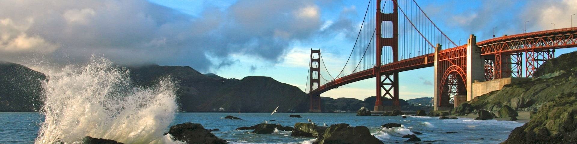 Playa Baker ofreciendo costa rocosa, vista panorámica y un puente