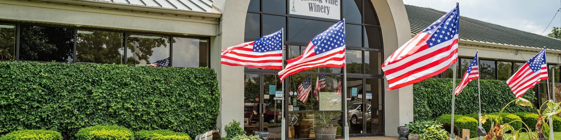 The Curling Vine Winery entrance with American flags and a well-maintained garden.