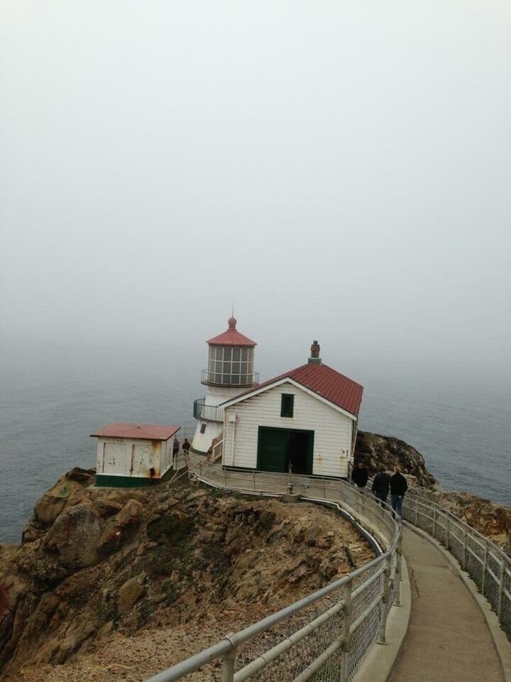 Un phare perché sur une falaise rocheuse, avec un chemin d’accès qui y mène.