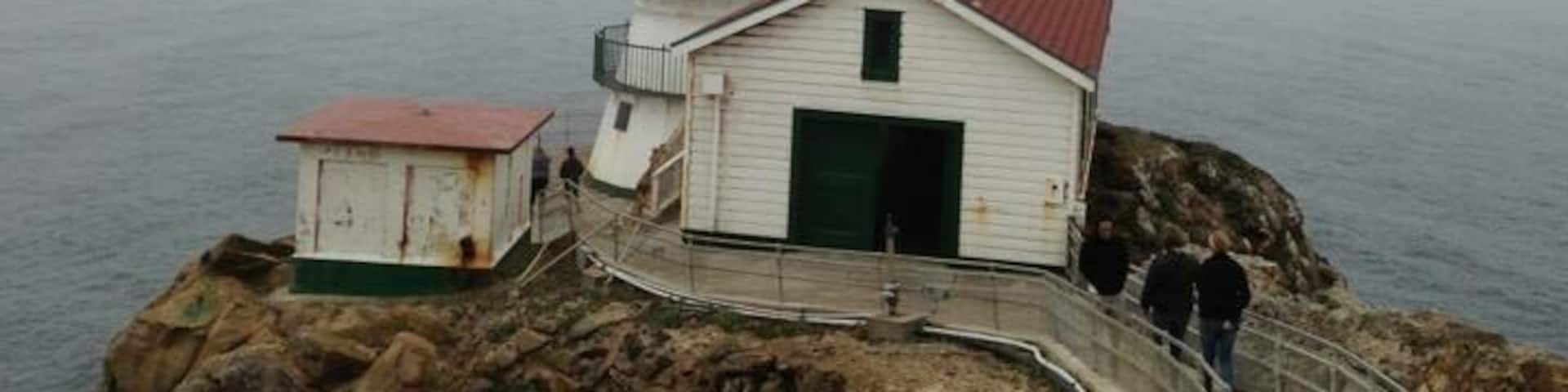 A lighthouse on a rocky cliff with a walkway leading up to it.