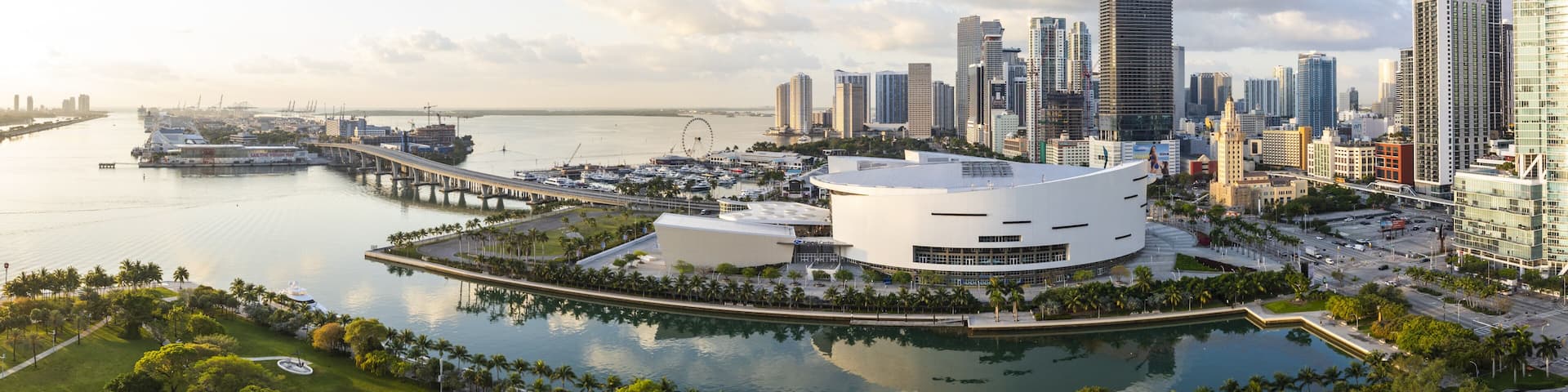 Aerial view of the Kaseya Center and the Miami skyline reflecting in the water, contrasting with the green park and the port, Miami, Florida, United States.