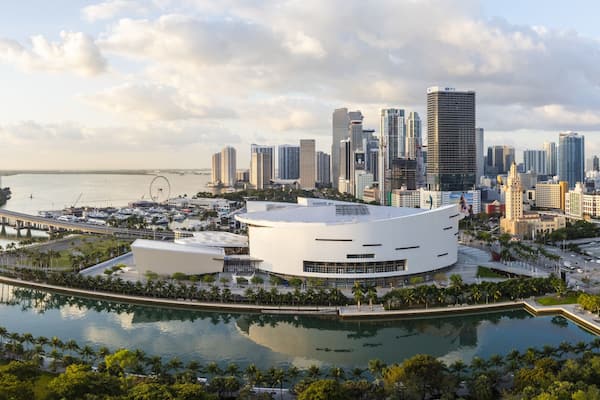 Aerial view of the Kaseya Center and the Miami skyline reflecting in the water, contrasting with the green park and the port, Miami, Florida, United States.