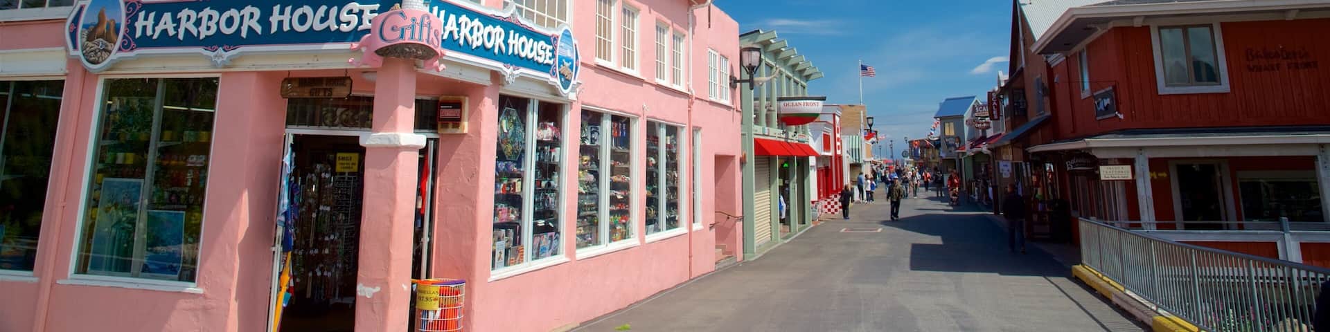 A pink building with a lighthouse, named Harbor House Gifts, and a red building across the street.