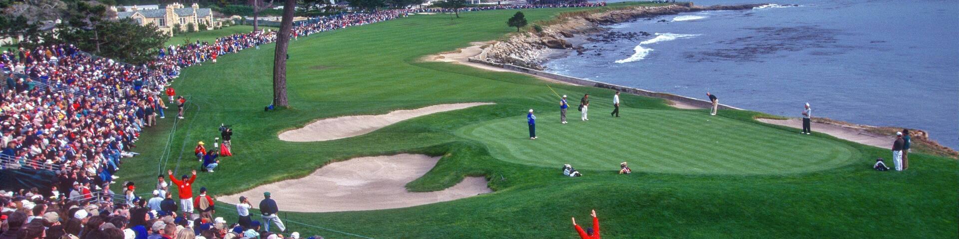 A golf course with spectators, a large crowd, and a coastal backdrop.