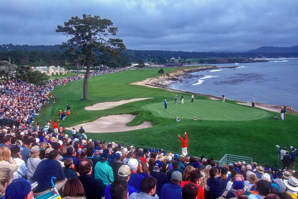 Un parcours de golf avec des spectateurs, une foule nombreuse et un paysage côtier en toile de fond.