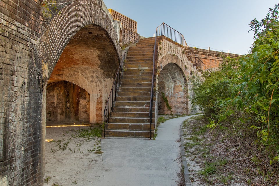 A historic brick staircase leading up to an arched bridge.