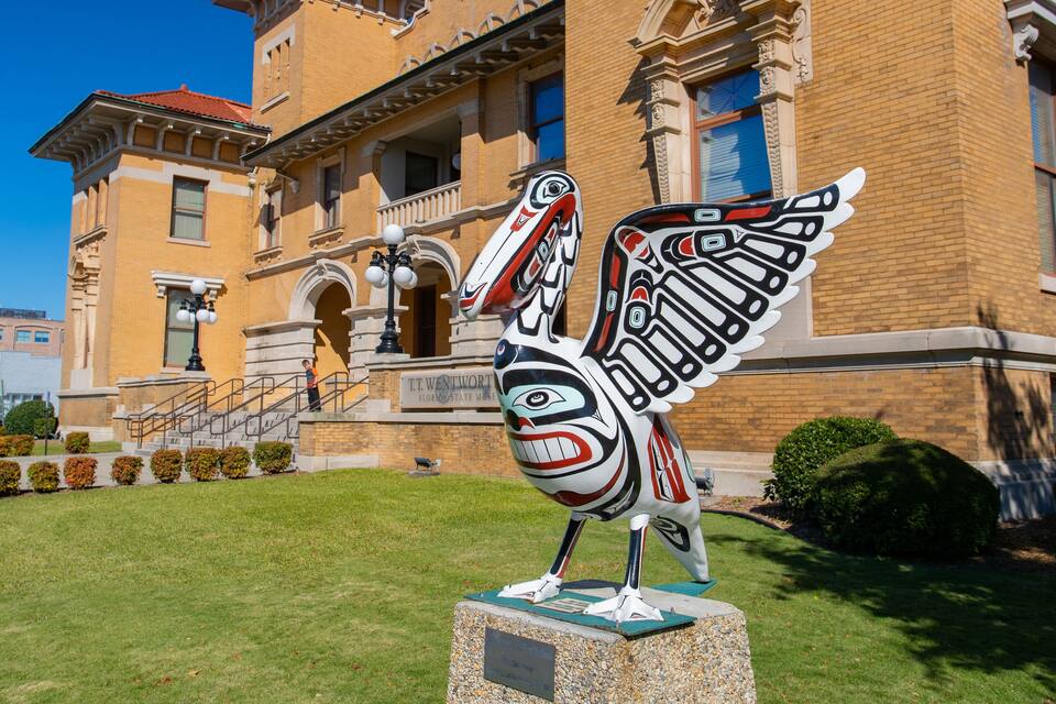 A totem pole in front of a historic building with a sign reading "T.T. Wentworth Florida State Museum".