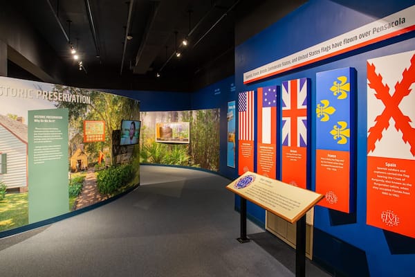 A museum exhibit with historical preservation information, flags, and a display about Pensacola.