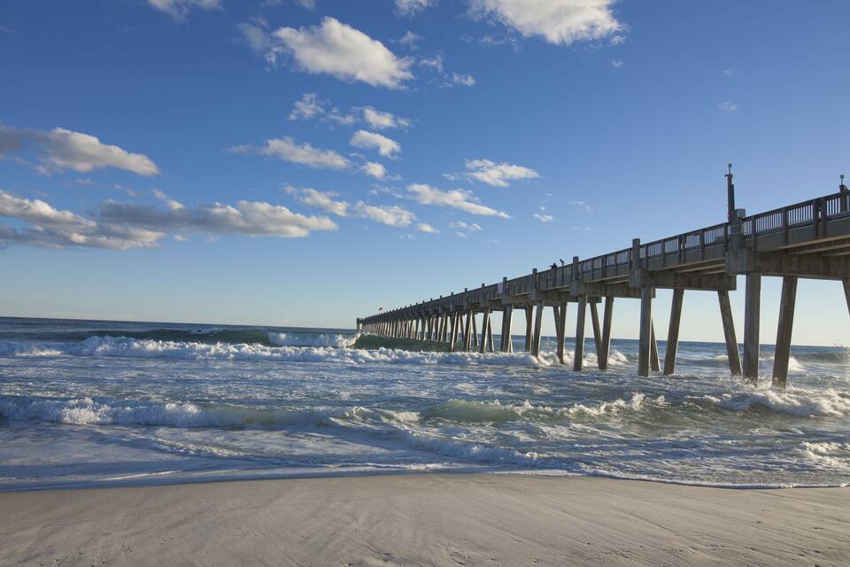 A pier extending into the ocean with waves crashing against it.