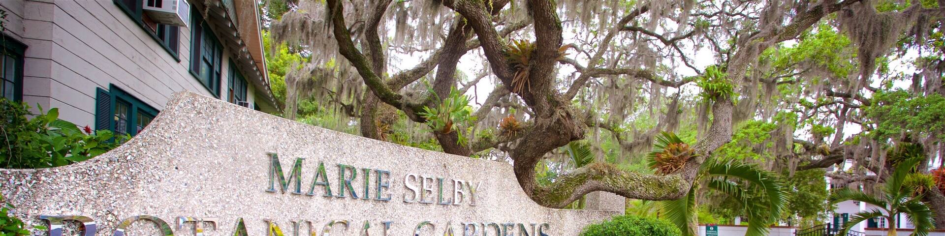 A sign for Marie Selby Botanical Gardens surrounded by lush greenery and trees.