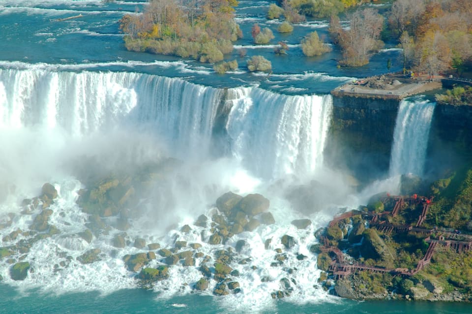 Una cascada grande con múltiples saltos, rodeada de terreno rocoso y árboles.