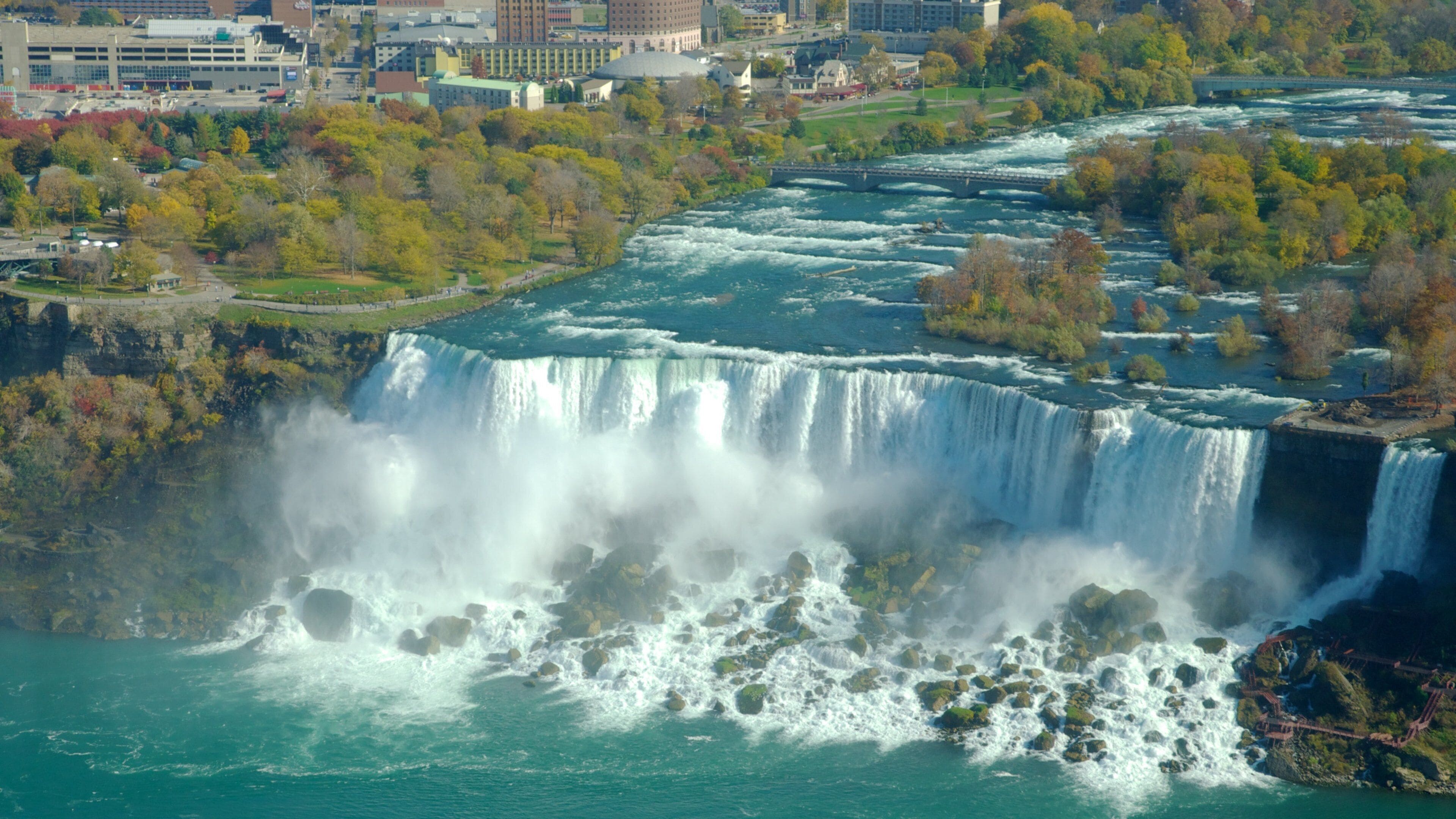 A large waterfall with a city in the background.