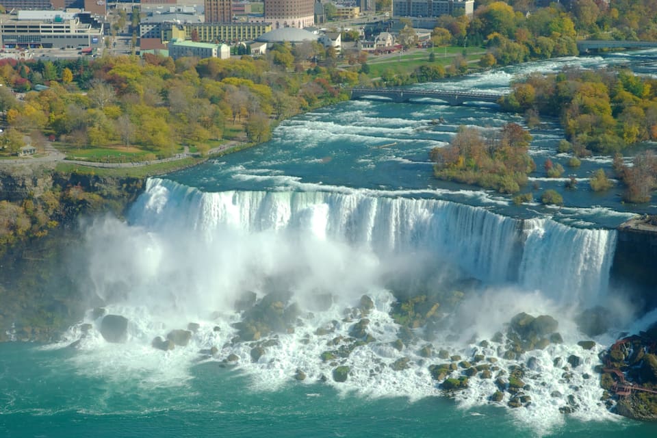 A large waterfall with a city in the background.