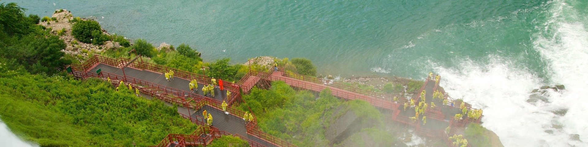 A waterfall with a red bridge and people in yellow raincoats.