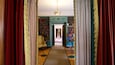 A grand hallway with red and white drapes, a chandelier, and bookshelves filled with books.