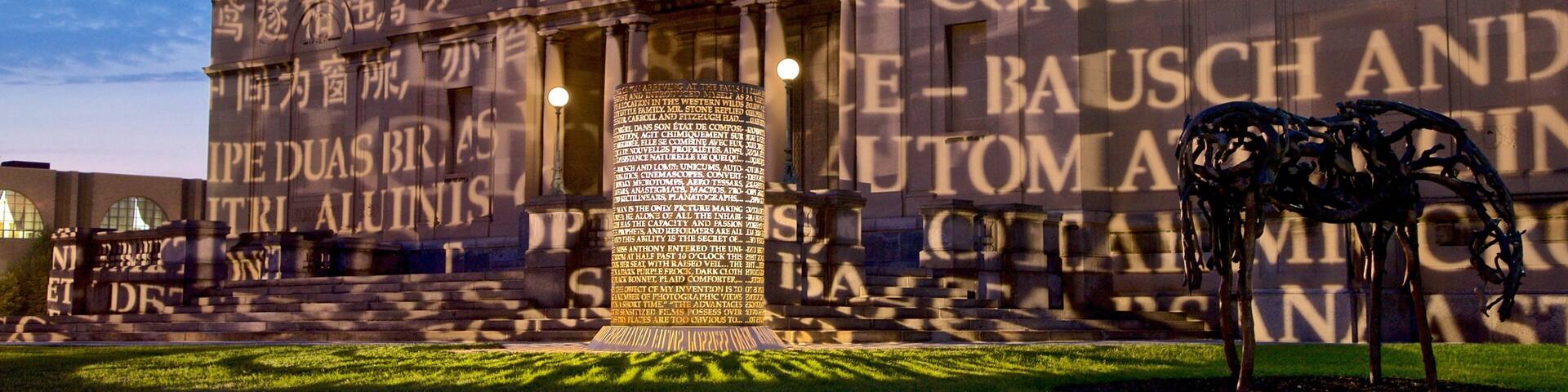 Fachada de un edificio con un texto grande y una escultura al frente.
