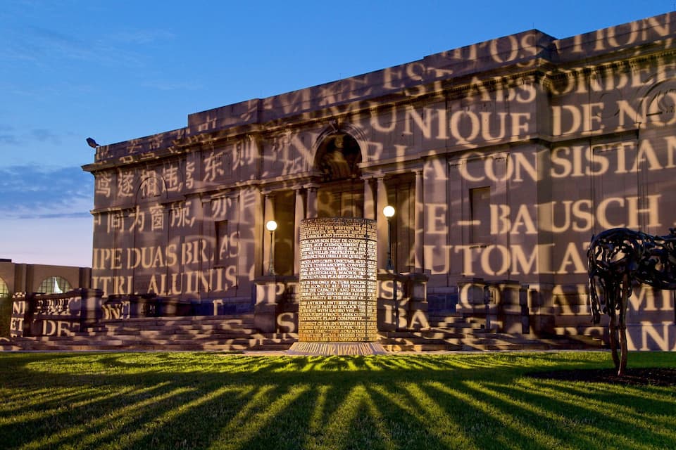 A building facade with large text and a sculpture in the foreground.