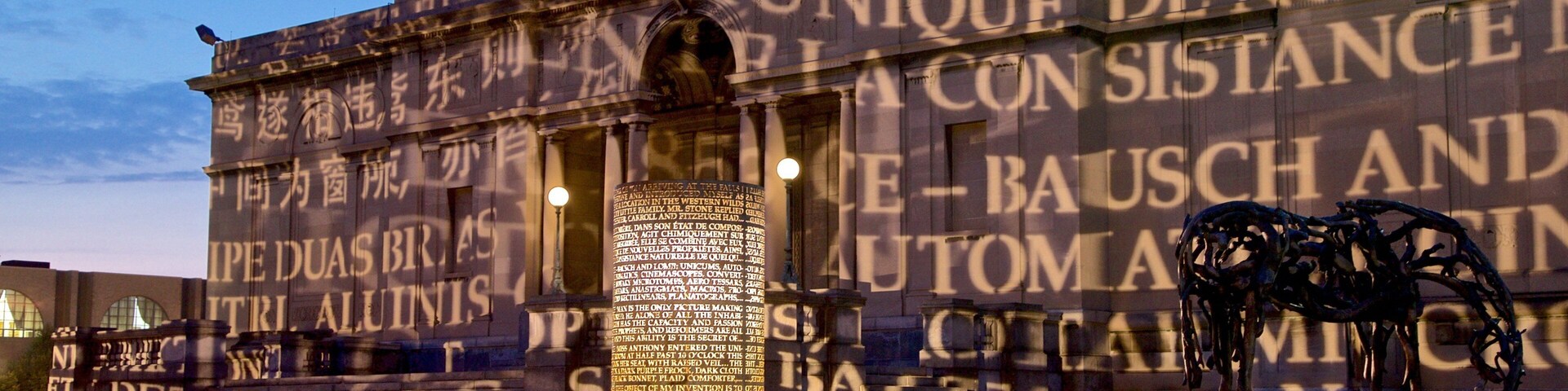 A building facade with large text and a sculpture in the foreground.