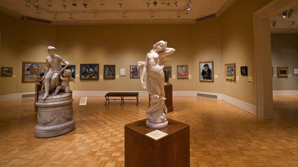 A museum interior with classical sculptures and framed paintings on the walls.