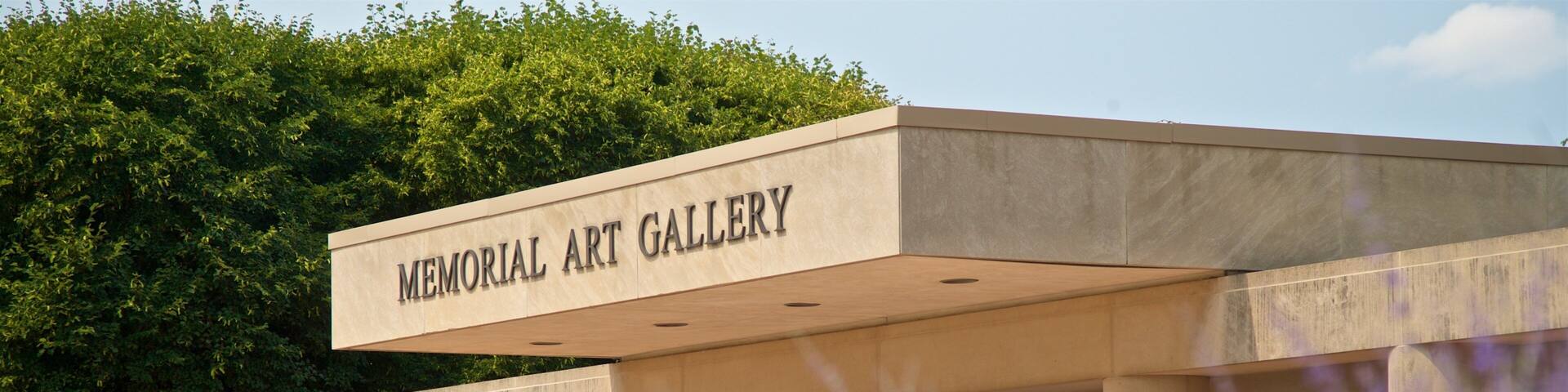 A building labeled "Memorial Art Gallery" with a modern architectural design, surrounded by trees and purple flowers.