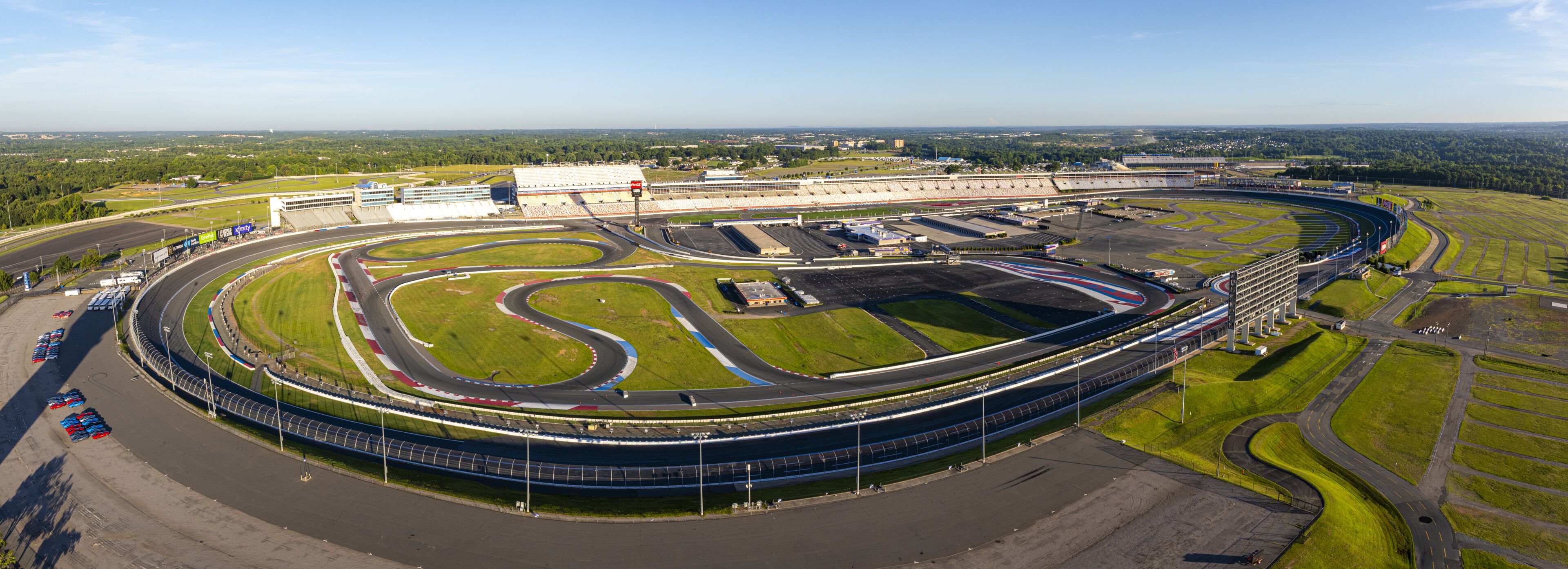 Concord, United States - 28 July 2025: Aerial view of Charlotte Motor Speedway's sprawling asphalt tracks and lush green infields under a clear blue sky.