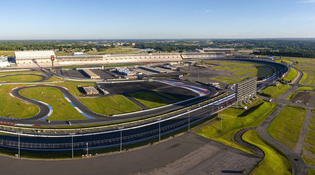 Concord, United States - 28 July 2025: Aerial view of Charlotte Motor Speedway's sprawling asphalt tracks and lush green infields under a clear blue sky.