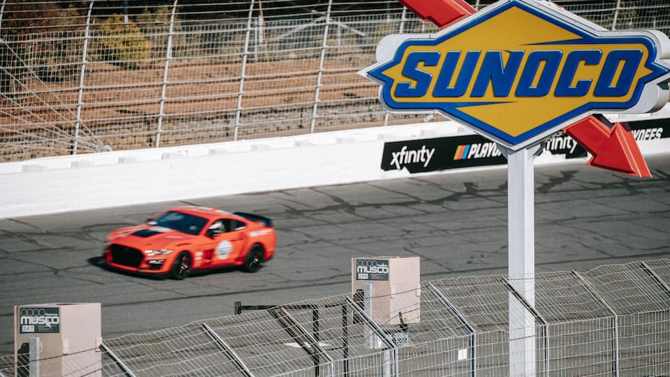 A racing car on a track with a 'SUNOCO' sign and 'Infinity' branding in the background.