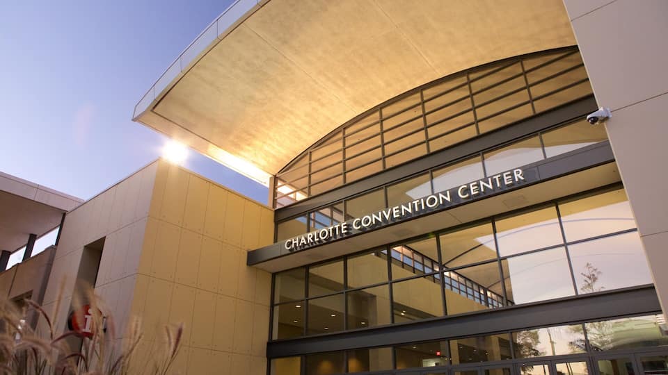 The exterior of the Charlotte Convention Center with a large glass facade and a sign reading "CHARLOTTE CONVENTION CENTER".