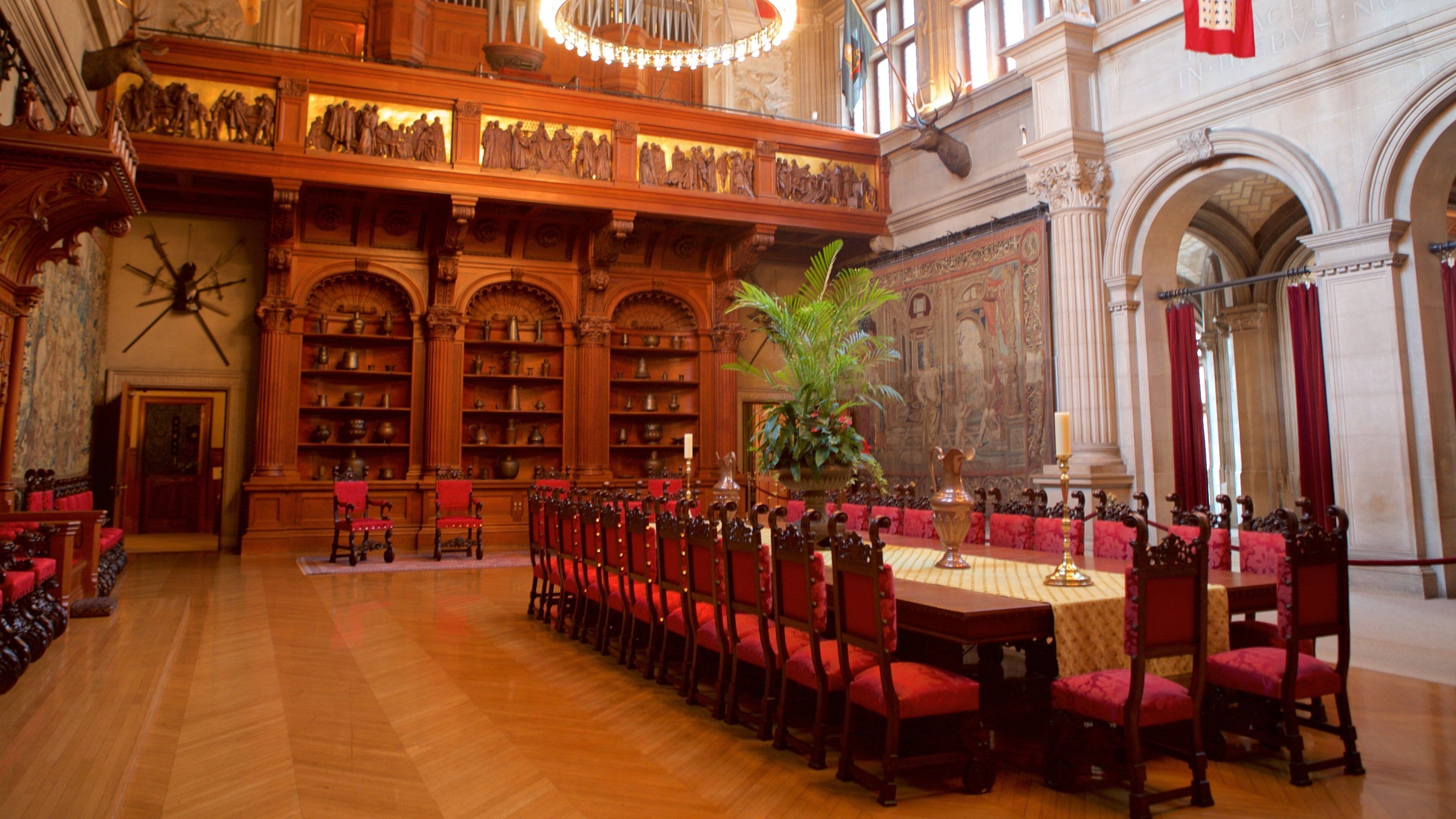 Eine prächtige Bibliothek mit Holzbögen, roten Sesseln und einem großen Tisch.
