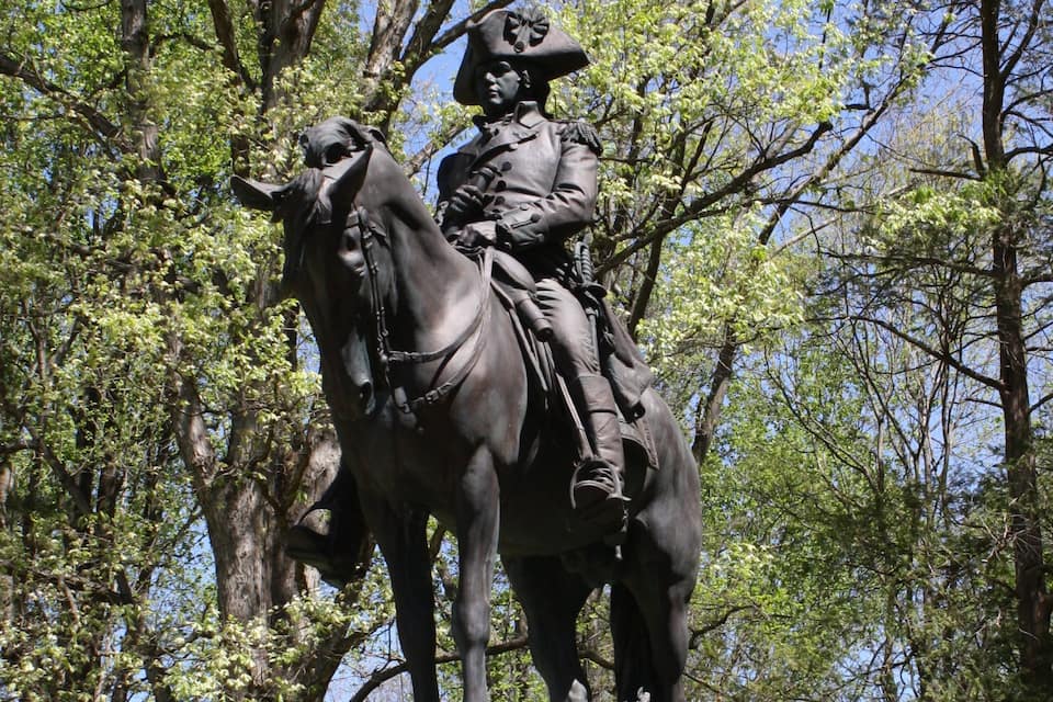 Una statua di un cavaliere a cavallo in una zona boschiva.