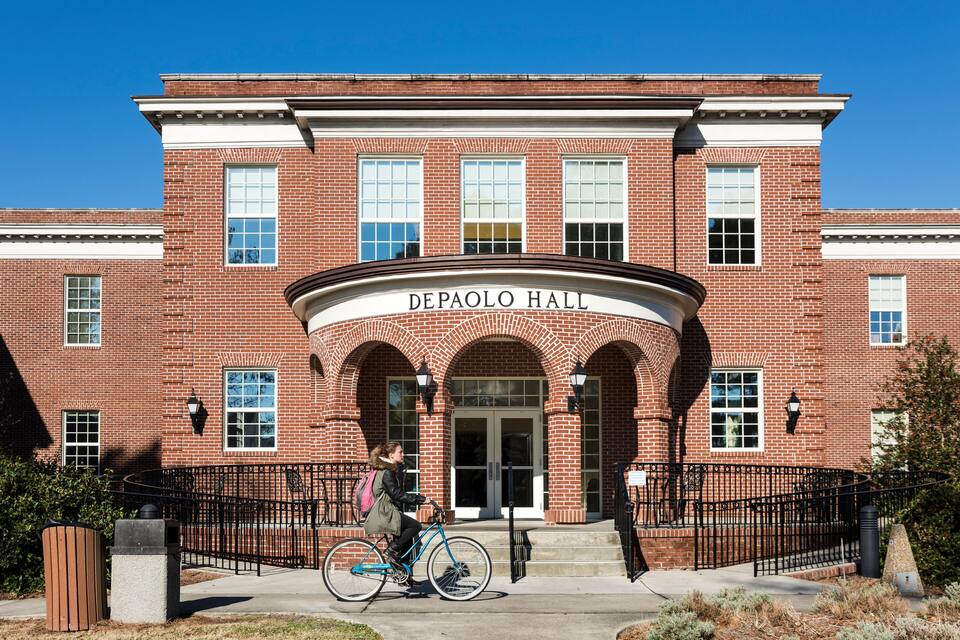A brick building with arched entrances and a sign reading "DePaolo Hall".