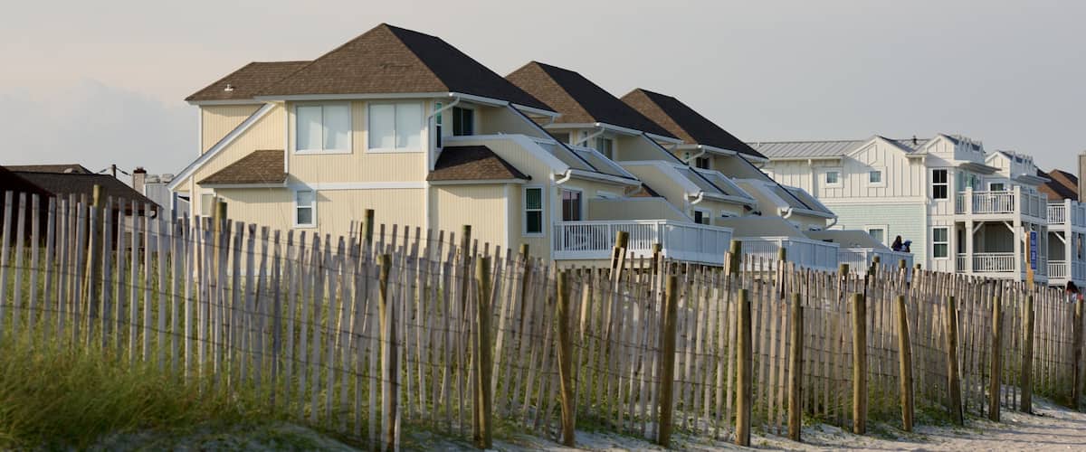 A row of beach houses with a wooden fence in the foreground.