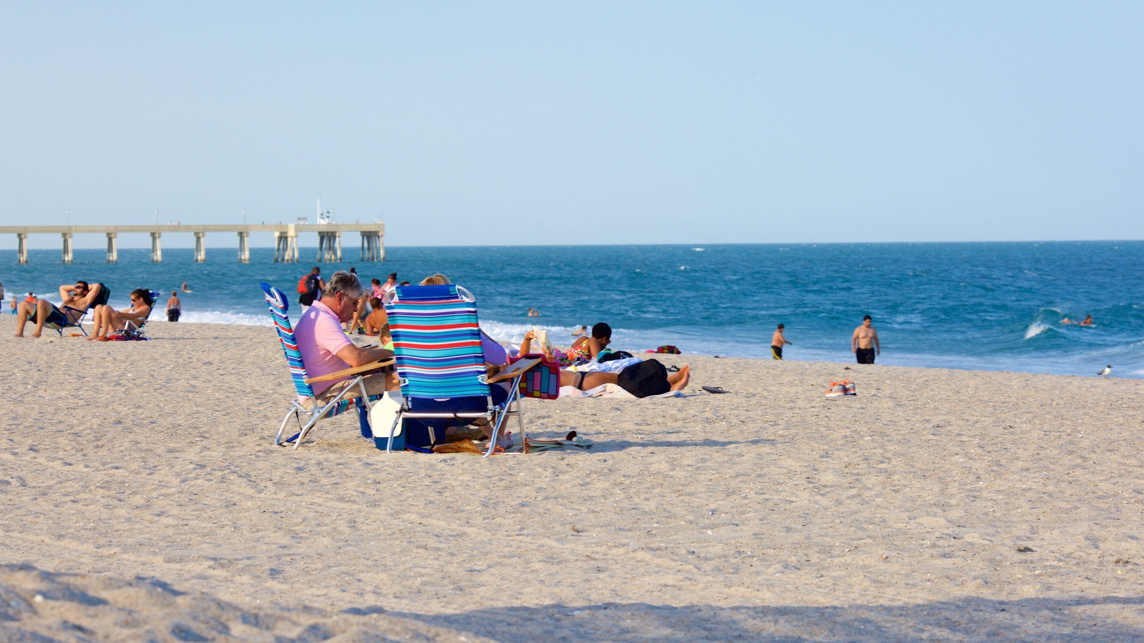 Una playa con gente tomando el sol y nadando.