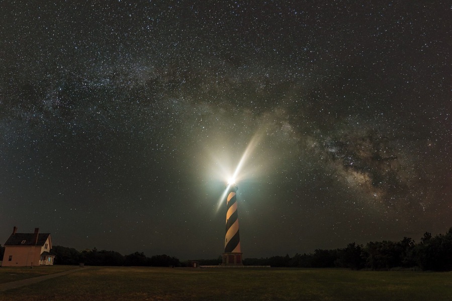 My first attempt at a serious panorama of the Milky Way, our home galaxy. Cape Hatteras Lighthouse provides an ideal location since it faces the right direction to compose such a panorama while maintaining the balance in the image.
This shot is composed of 6 vertical shots shot at 30 degrees of rotation and merged in Photoshop. Added to the usual difficulties of shooting and composing a panorama at night, this night was crazy hot with nighttime temperature in the mid 80s, no breeze and humidity so high that the lens had to be wiped after every exposure. On top of it, the mosquitoes had a field day running rings around me and no amount of bug spray helped. But in spite of all that, I managed to walk away with an image and experience that does appeal to me.