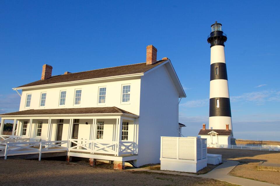 Uma casa branca com um farol preto e branco nas proximidades.