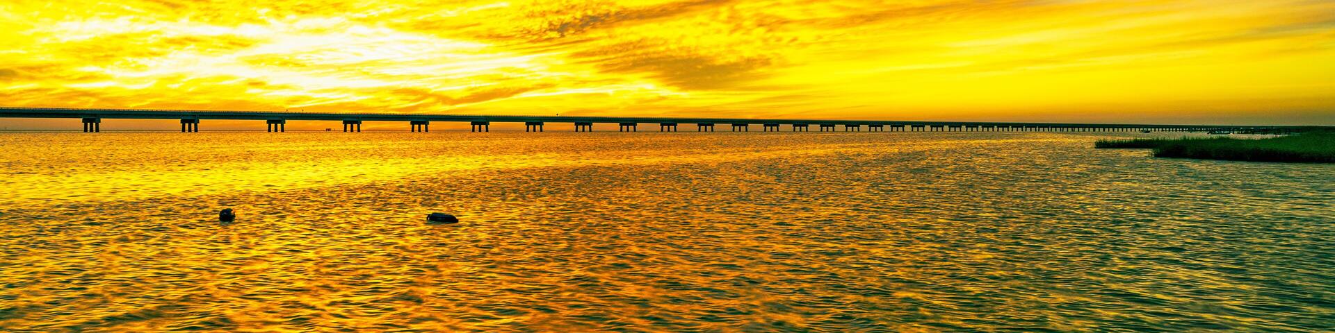 A sunset over a body of water with a pier extending into the water.