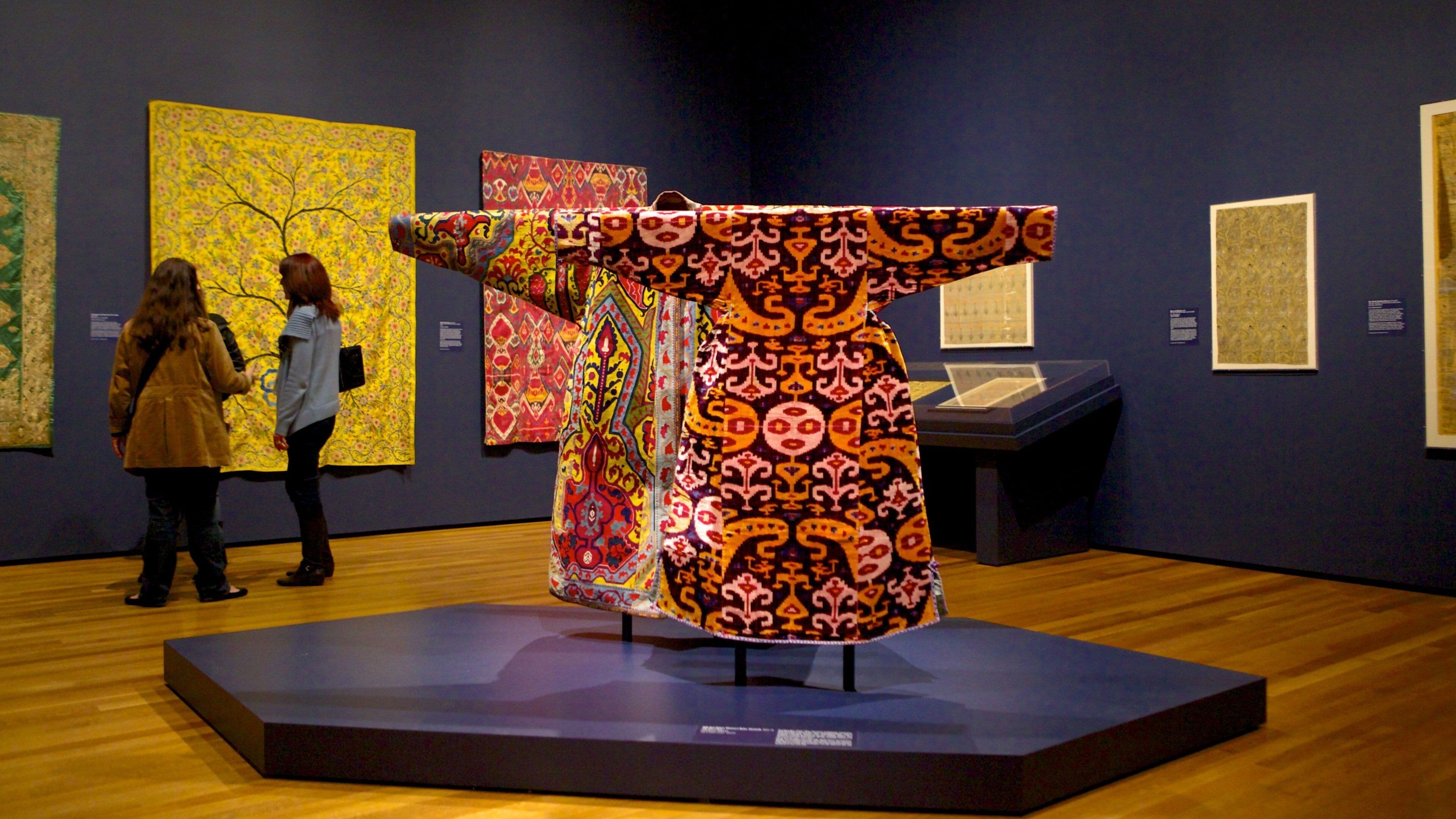 An art gallery with colorful textiles on display.