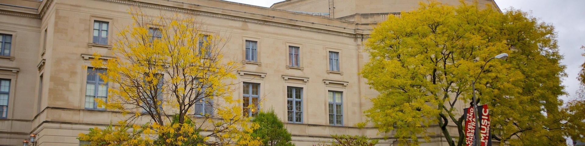 Ein großes, historisches Gebäude mit klassischer Architektur, umgeben von Bäumen mit Herbstlaub und einem gepflegten Rasen.