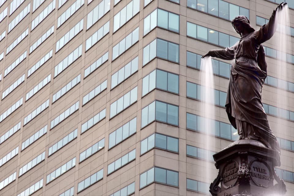 A statue of a woman with raised arms, standing on a pedestal with the inscription "To the People of Cincinnati" and "Tyler Davidson" on it.
