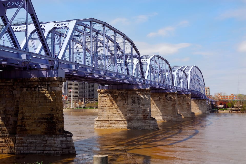 Un puente de celosía de acero sobre un río, con pilares de ladrillo.