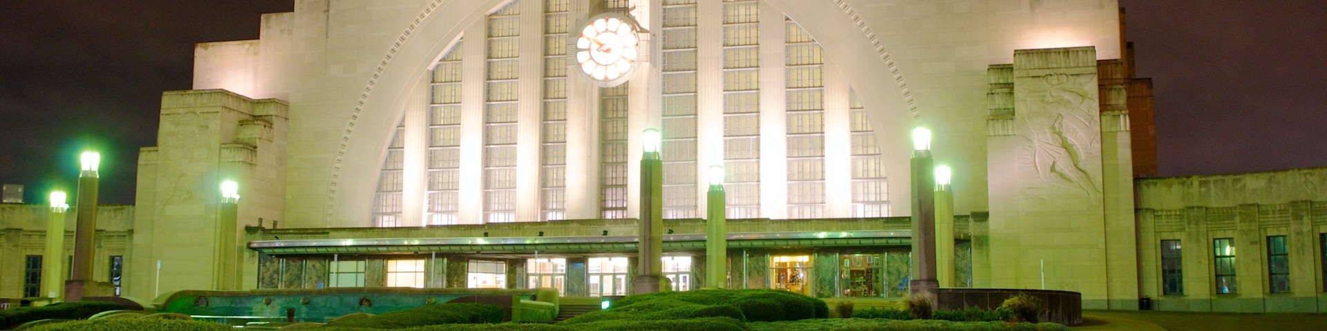A large, illuminated building with a central clock tower and arched windows.