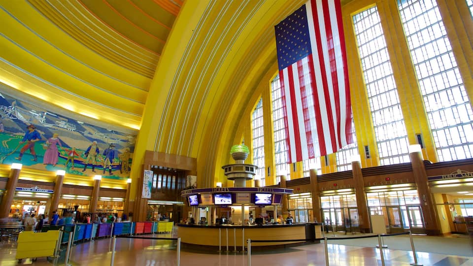A spacious indoor area with a large American flag, a ticket counter, and a mural on the wall.