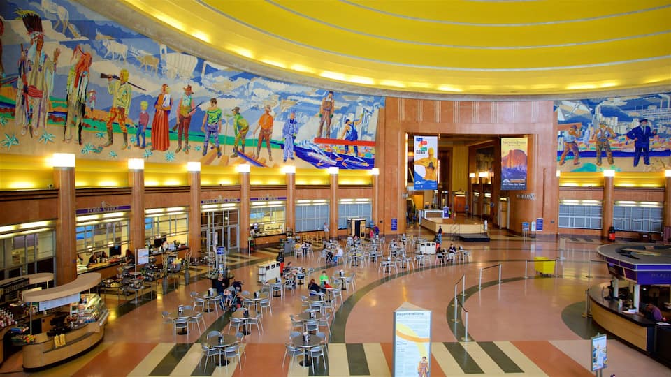 A spacious lobby with a mural depicting historical scenes, a ticket counter, and seating areas.