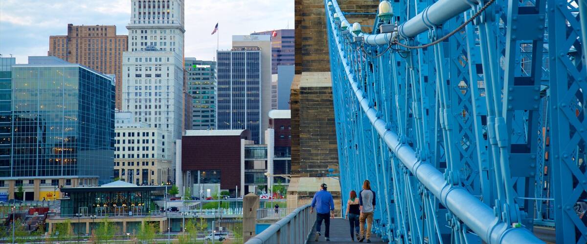 A blue bridge with pedestrians, a city skyline with a prominent building labeled 'PNC', and modern architecture.