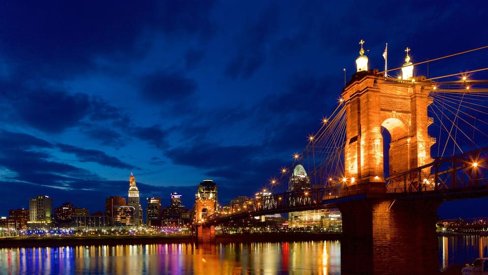 A nighttime cityscape with a prominent bridge and illuminated buildings.