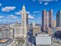 A cityscape with a prominent Art Deco building, modern high-rises, and a busy intersection.