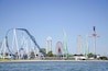 A coastal amusement park with roller coasters and a Ferris wheel.