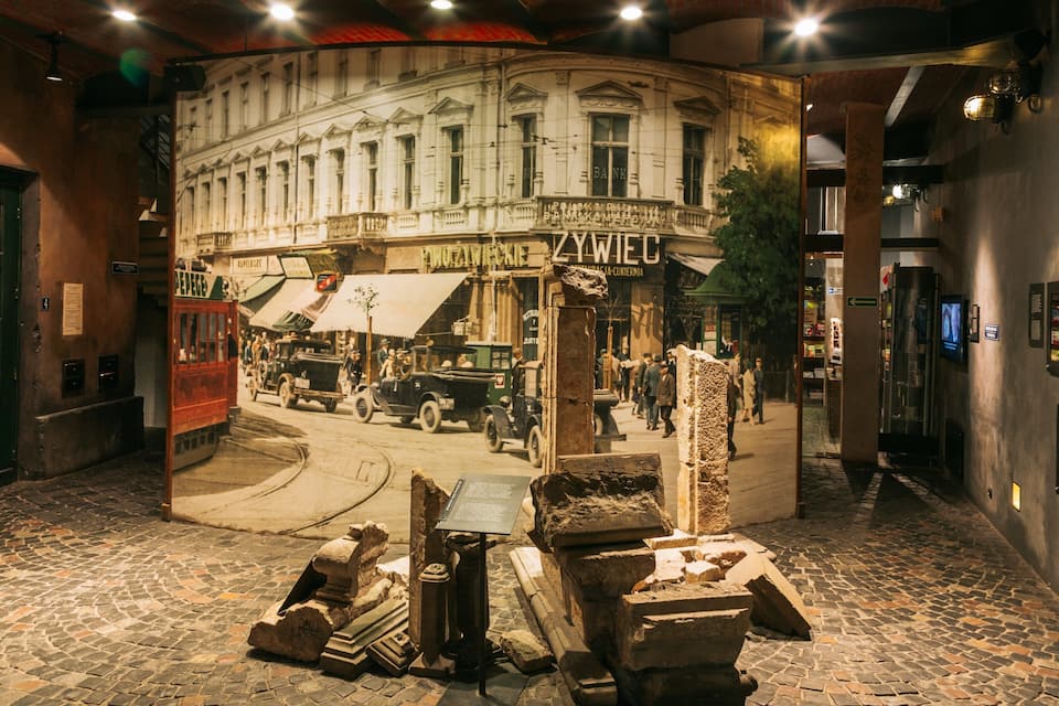 A historical street scene with cobblestone pavement, vintage cars, and a building labeled "Bank".