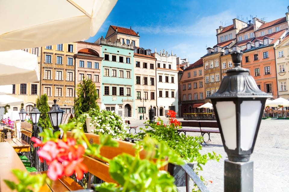A cobblestone square with colorful buildings, a wooden bench, and a street lamp.