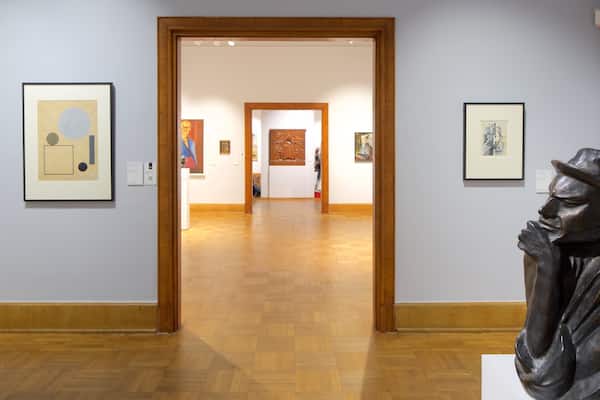 Une galerie d’art dotée de planchers en bois et dont les murs sont ornés d’œuvres d’art encadrées.